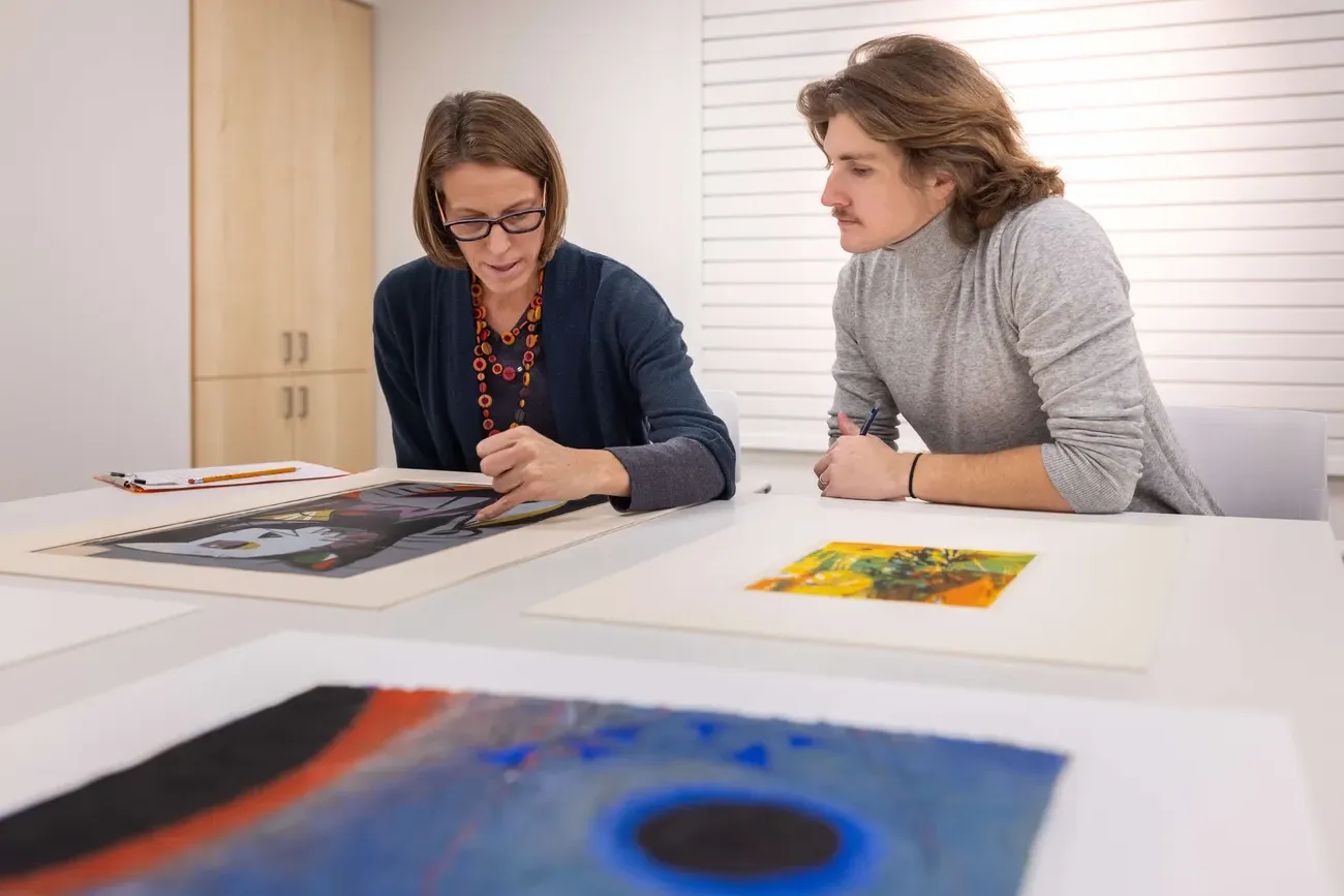 Professor Sascha Scott looking at art with a student.